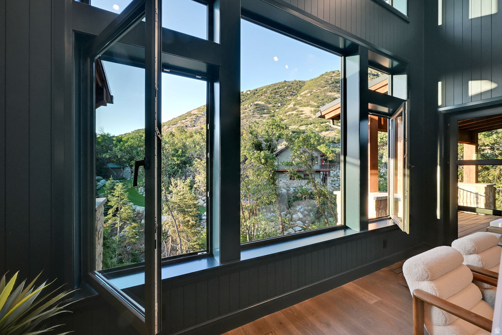 Expansive picture windows with operable sections frame a mountainous, tree-lined landscape
