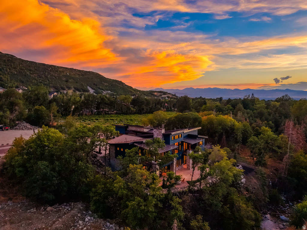 Expansive property featuring a multi-level residence with natural stone and wood siding, surrounded by mature trees
