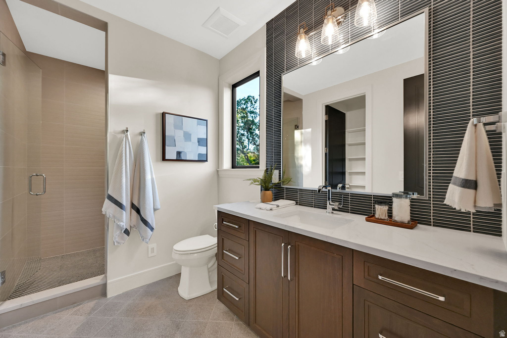 Contemporary bathroom featuring a spacious glass-enclosed shower with tile surround, a dark wood-finish vanity with ample storage, a white countertop, and a large mirror with integrated lighting
