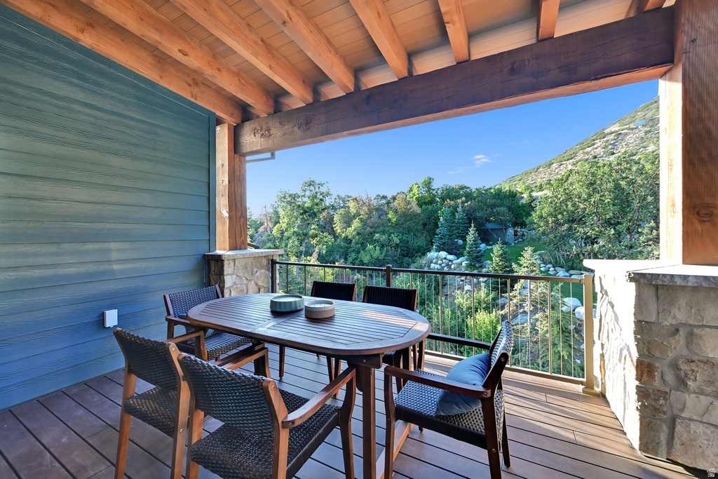 Covered outdoor deck with wood-finish flooring, stone-clad pillars, and a wood beam ceiling