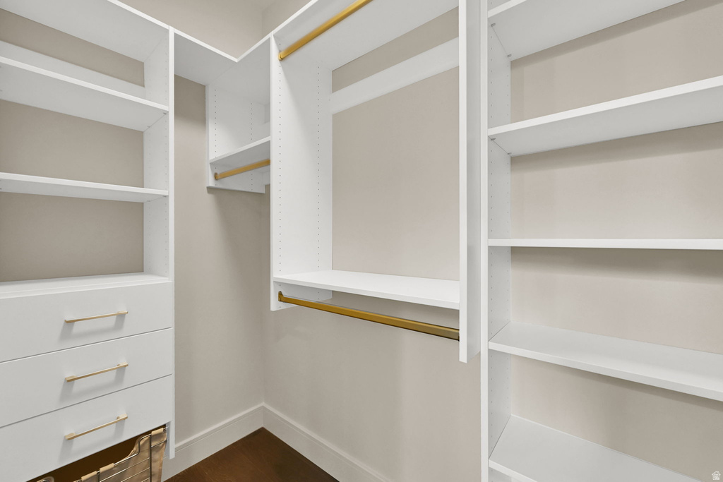 Built-in closet system featuring white shelving, integrated drawers with gold-tone hardware, and multiple hanging rods