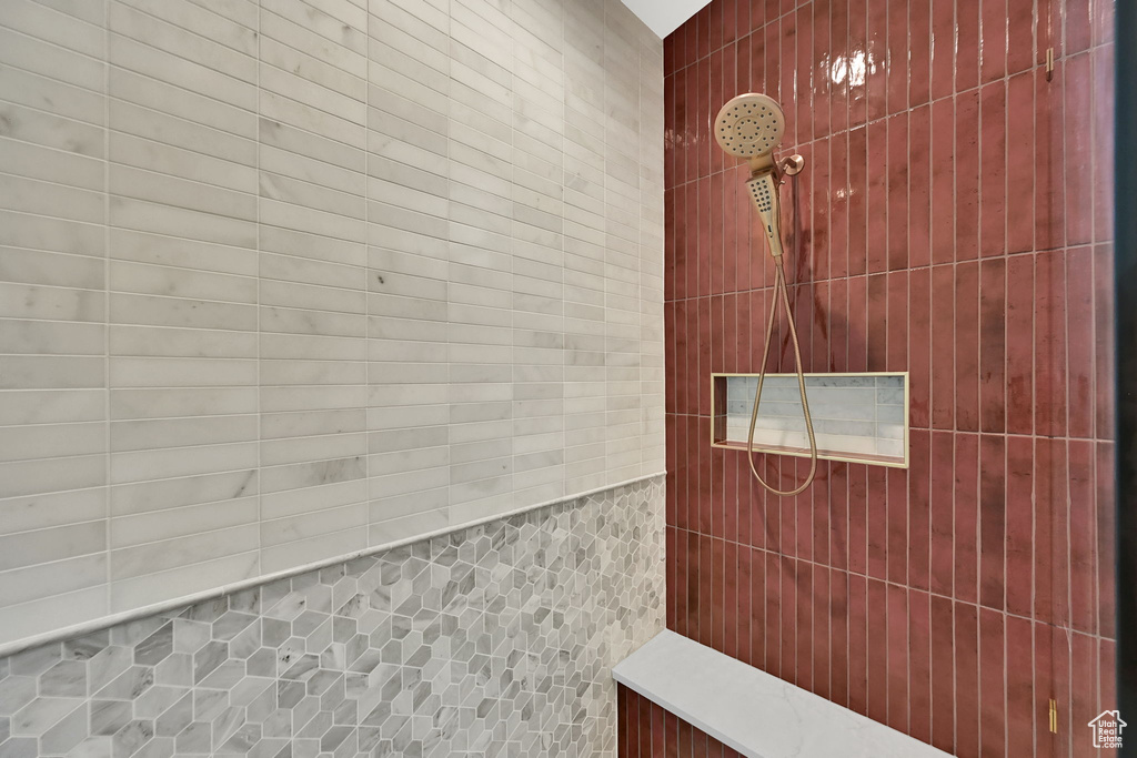 Shower enclosure featuring a built-in bench, recessed niche, and a combination of red vertical subway tiles, grey geometric mosaic tiles, and white horizontal subway tiles