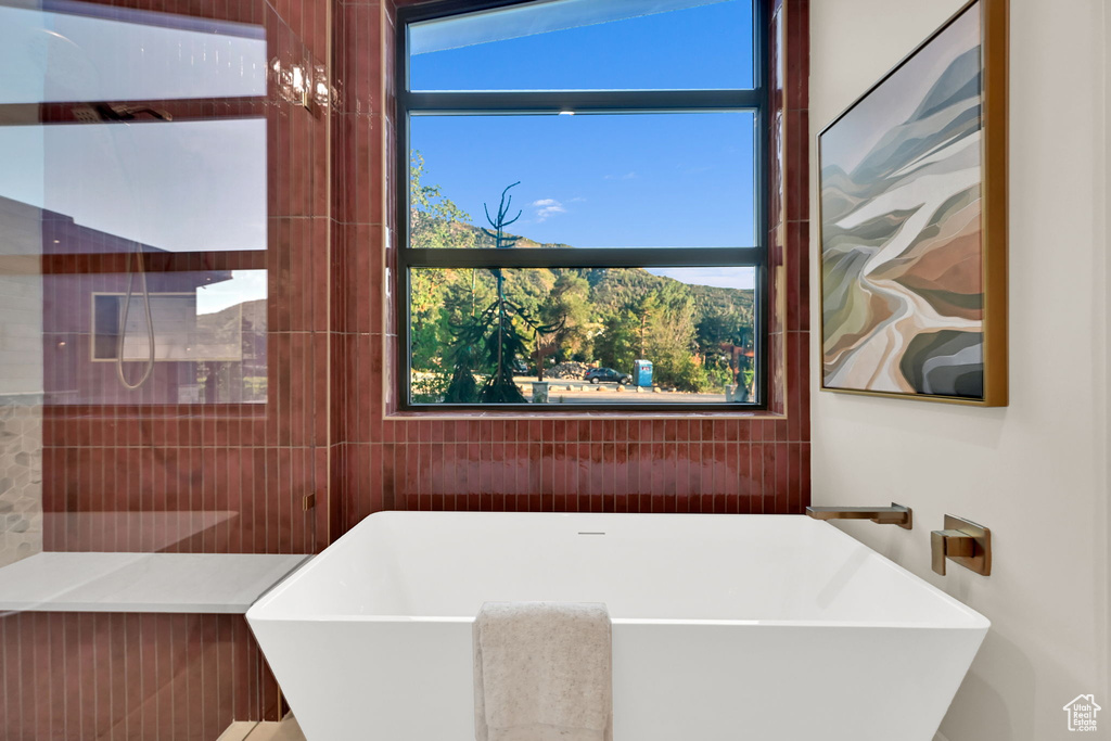 Freestanding soaking tub with wall-mounted bronze fixtures, set against a backdrop of terracotta vertical tile