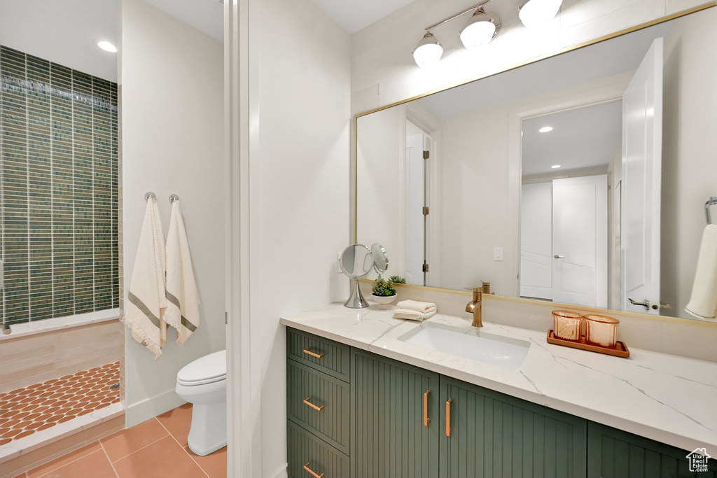 Bathroom featuring a green slatted vanity with copper hardware, a white countertop with an integrated rectangular sink, a gold-framed mirror, and a walk-in shower with green mosaic tile