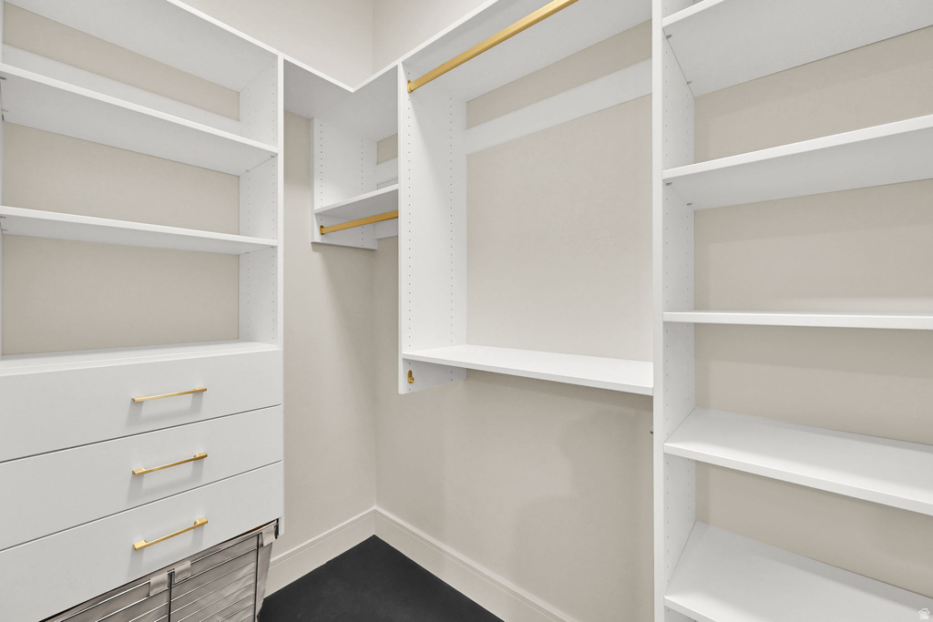 Custom closet system featuring white shelving and drawers with gold-tone hardware