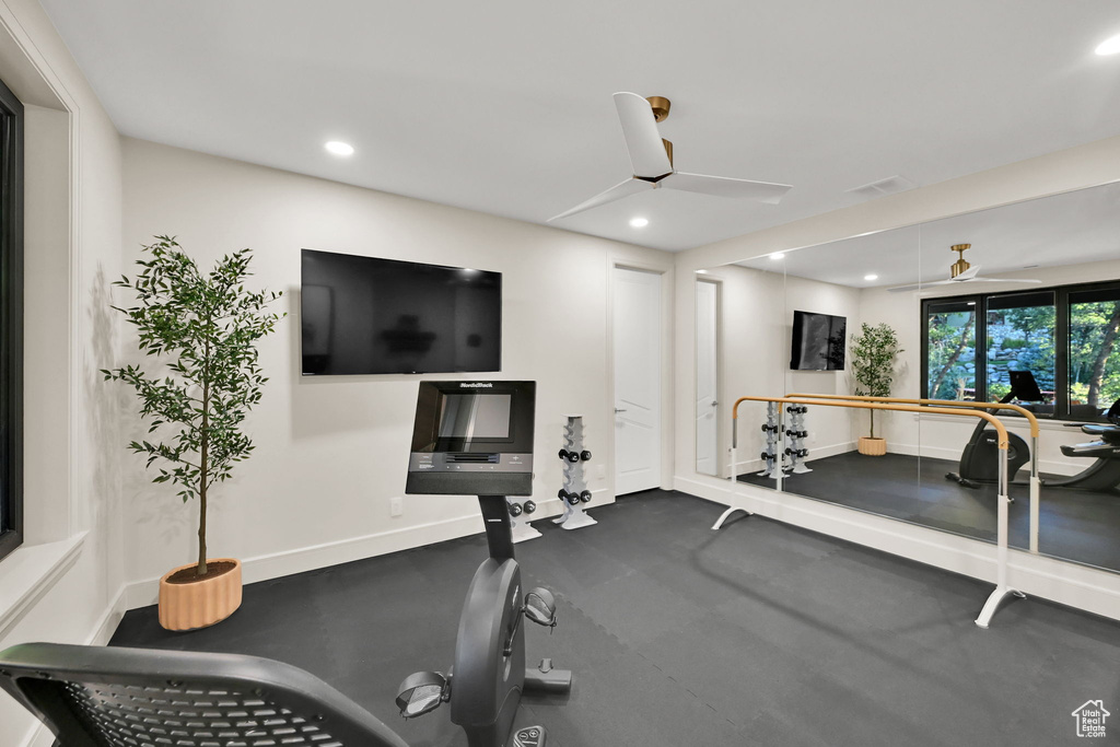 Dedicated fitness space featuring rubberized flooring, a full-wall mirror, and a ballet barre