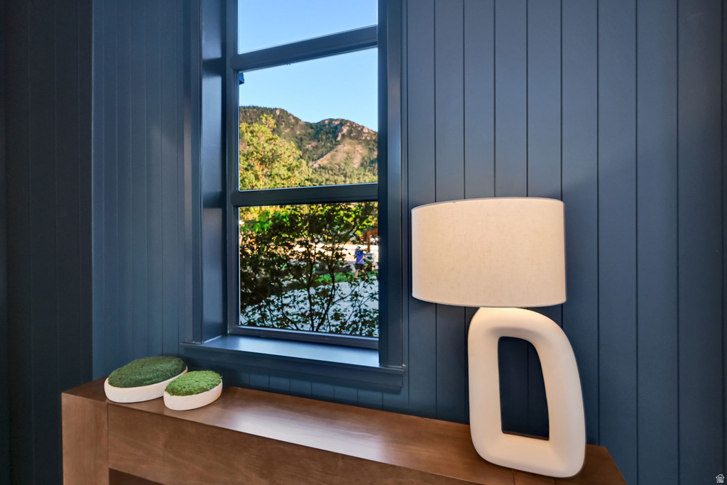 Window with mountain scenery, vertical paneled wall, and wood-finish console