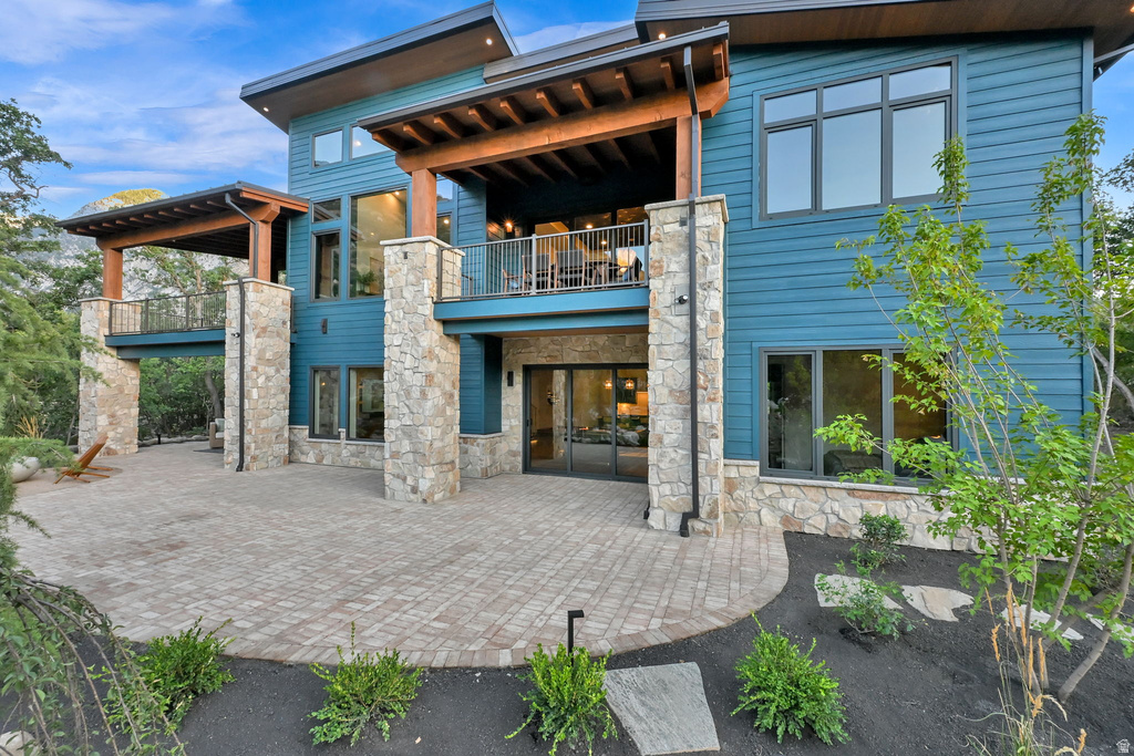Multi-level contemporary exterior featuring stone columns, blue horizontal siding, and extensive window placements