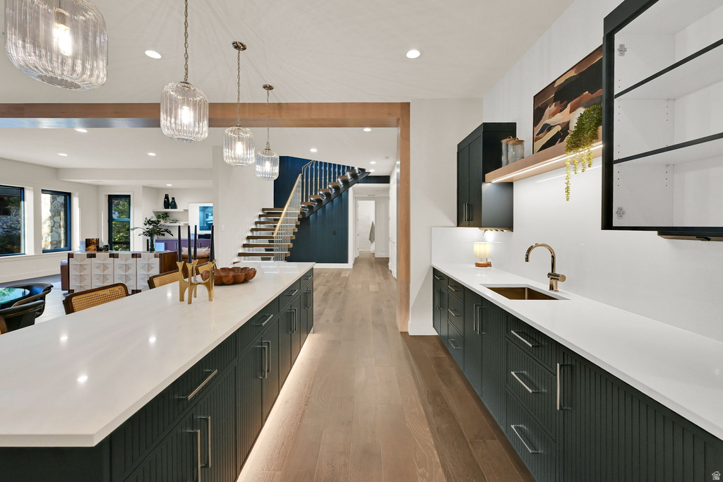 Expansive kitchen island and wet bar featuring white countertops and dark cabinetry