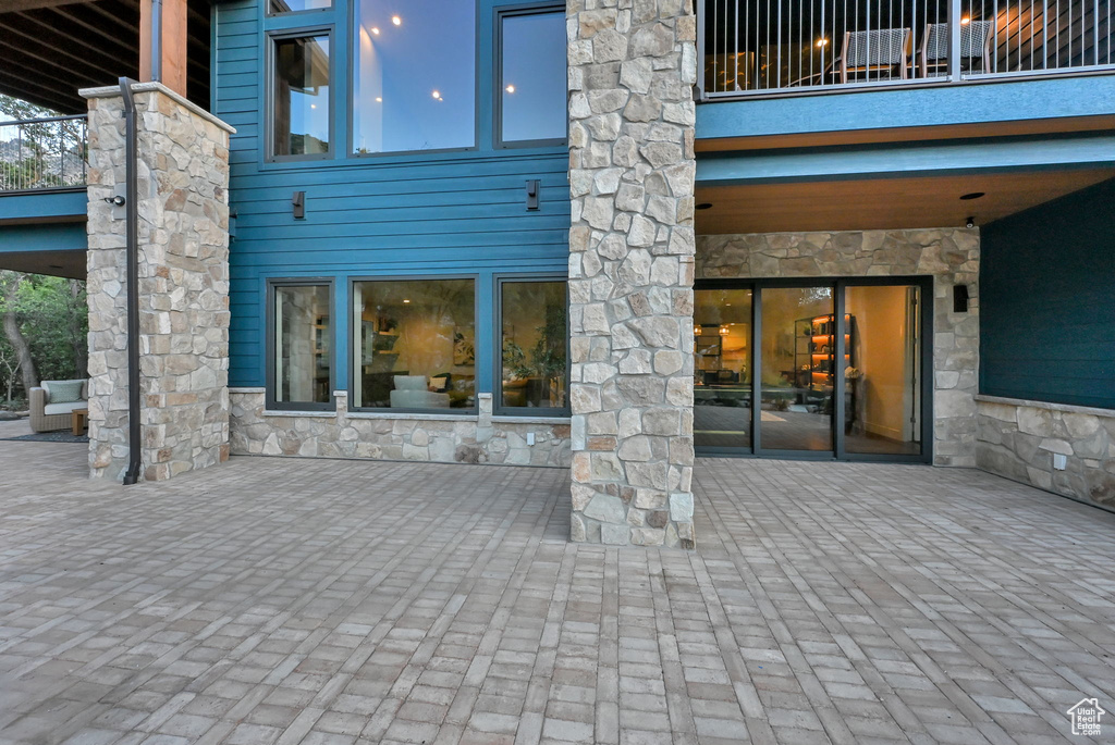Expansive paver patio with a stone and wood-paneled exterior