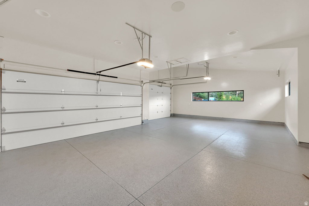 Spacious two-car garage featuring a light gray epoxy floor and white sectional garage doors