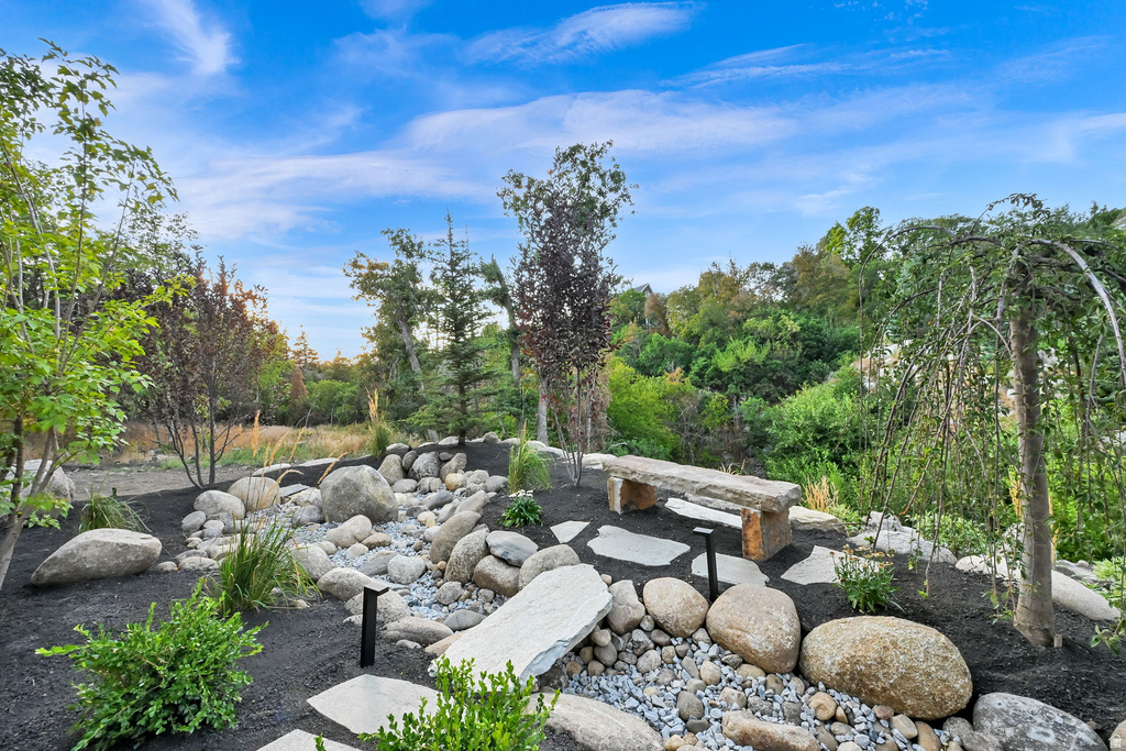 Landscaped rock garden featuring a stone bench, irregular stone pavers, and varied plantings