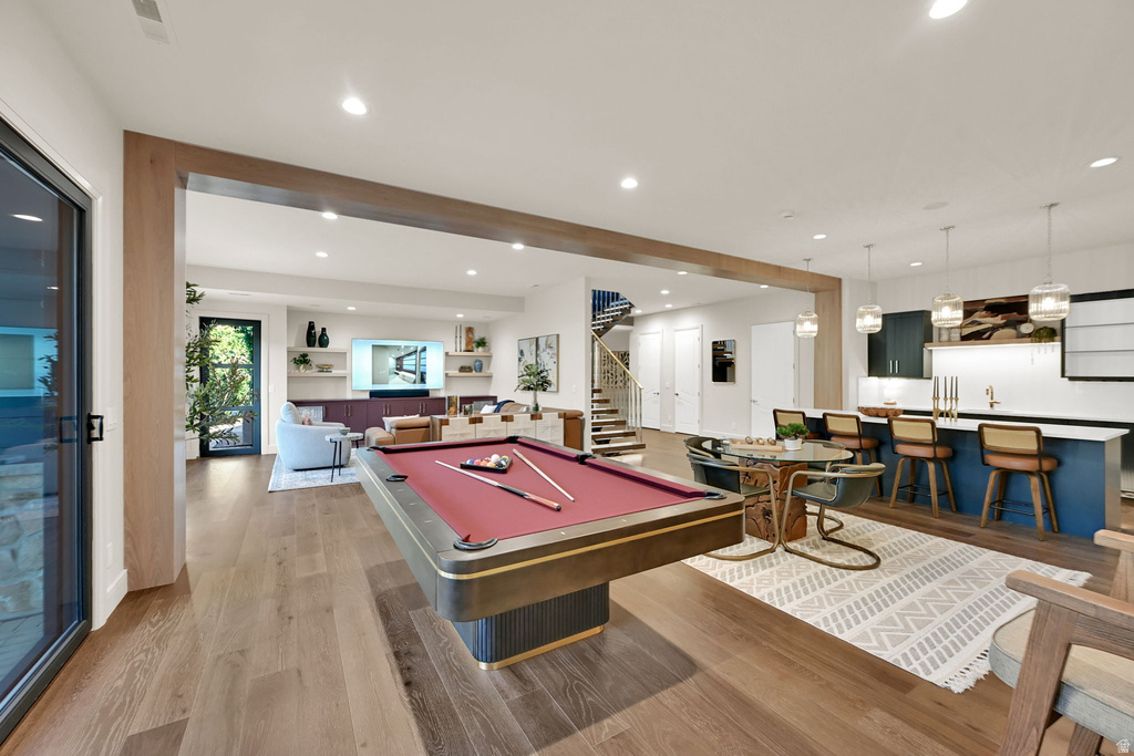 Open-concept living area featuring wide plank wood-finish flooring, recessed lighting, and a prominent wood beam detail