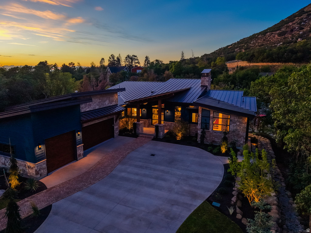 Modern-rustic residence featuring stone and horizontal siding exterior, a metal roof, and an attached two-car garage