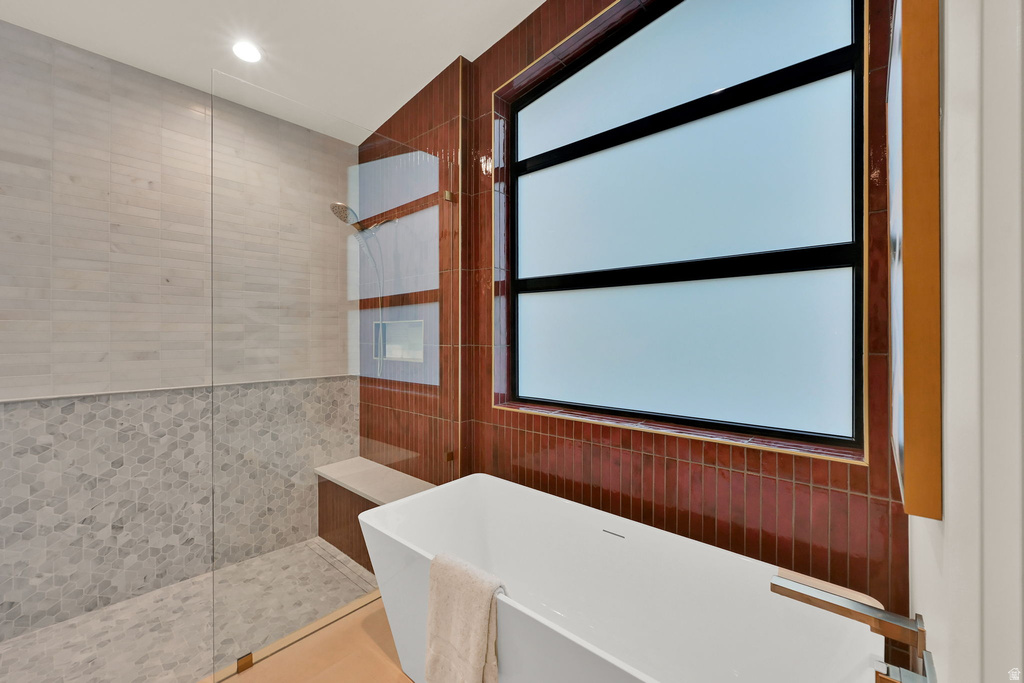 Contemporary bathroom featuring a freestanding tub with wall-mounted fixture, a frosted window with dark trim, and a shower enclosure with a built-in bench