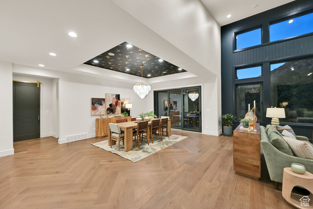 Spacious interior featuring chevron wood-finish flooring, a tray ceiling with recessed lighting, and a decorative chandelier