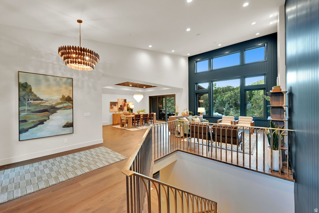 Open-concept living area featuring a double-height ceiling, extensive window wall, wood-finish flooring, and a contemporary chandelier