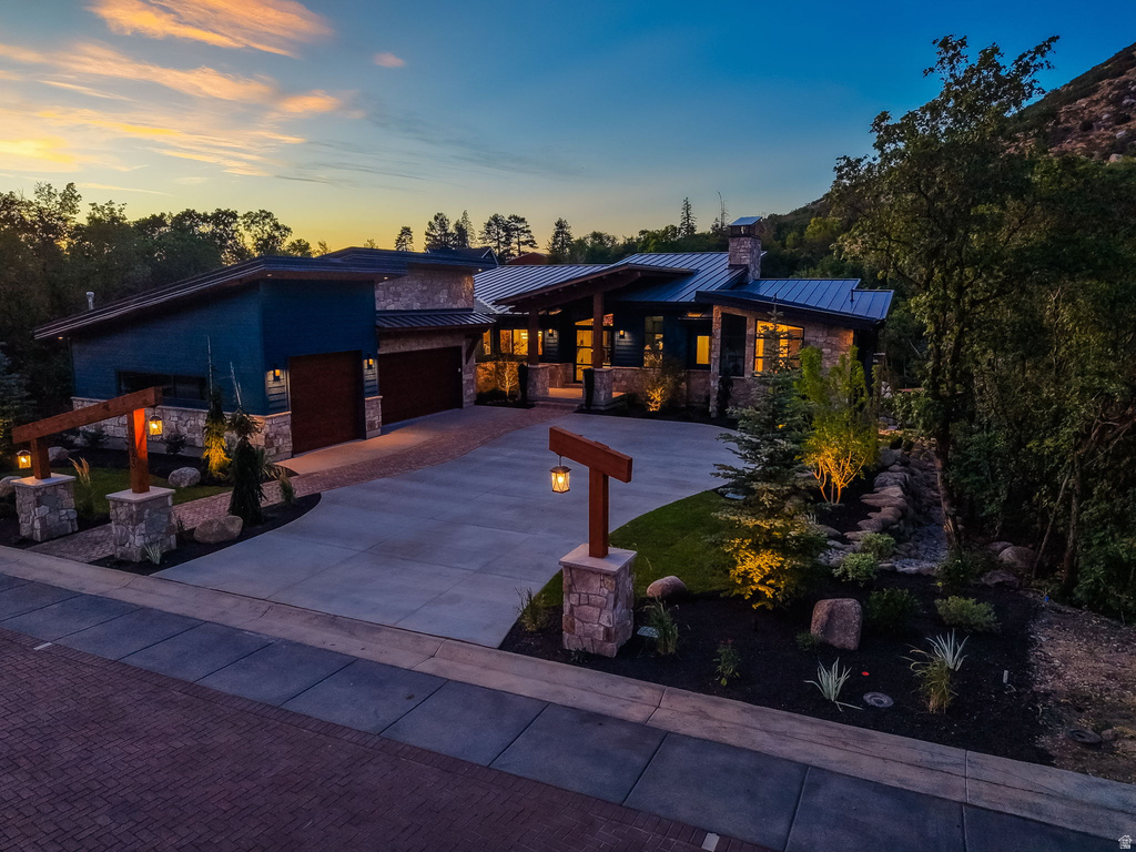 Contemporary architectural design featuring stone facade accents, a metal roof, and a multi-car garage