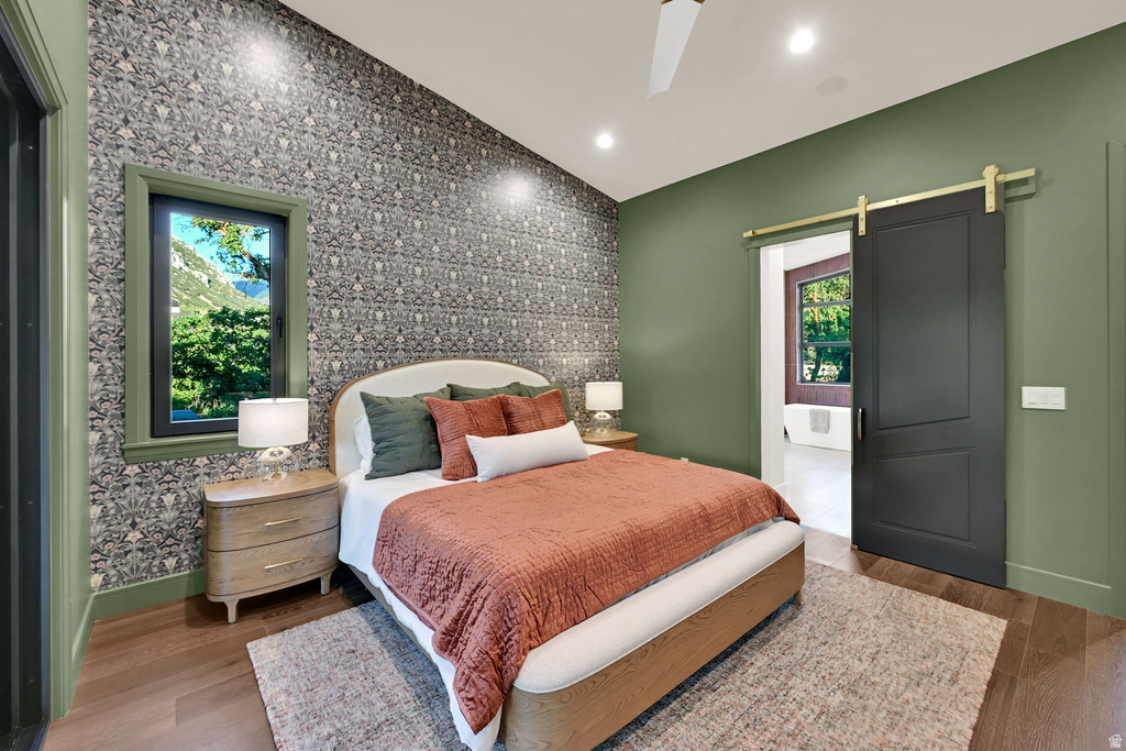 Bedroom with a patterned accent wall, recessed lighting, and wood-finish flooring