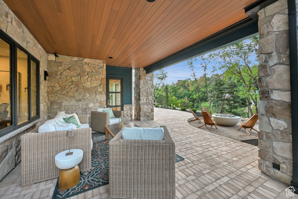 Covered outdoor patio featuring stone columns and walls, a wood-finish ceiling, and a brick paver patio