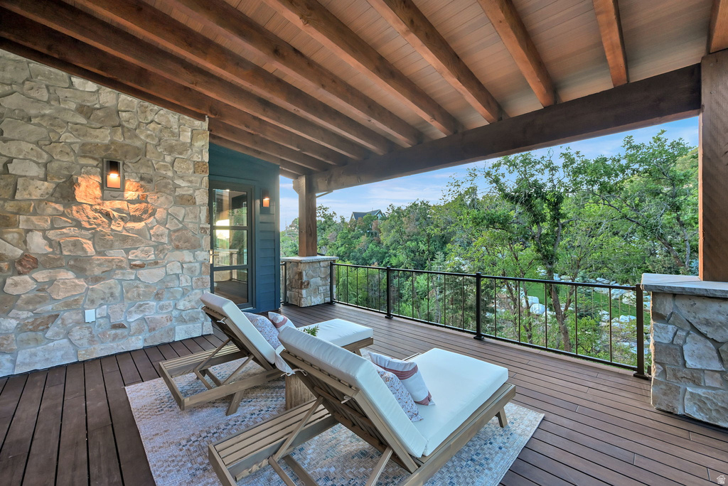 Spacious covered deck featuring a natural wood-finish ceiling with exposed beams, composite decking, and a stone accent wall