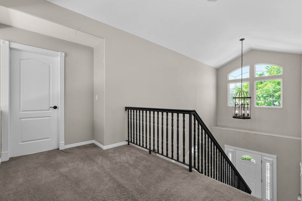 Upper-level hallway featuring plush gray carpeting, a white paneled door with black hardware, and a black wrought iron staircase railing