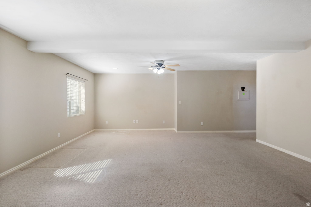 Spacious room featuring neutral carpeting, a ceiling fan with light, and a window with horizontal blinds