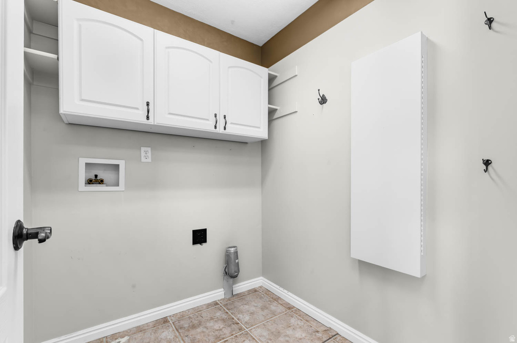 Utility room featuring overhead white cabinetry with arch panel doors and dark hardware, open shelving, and tiled flooring