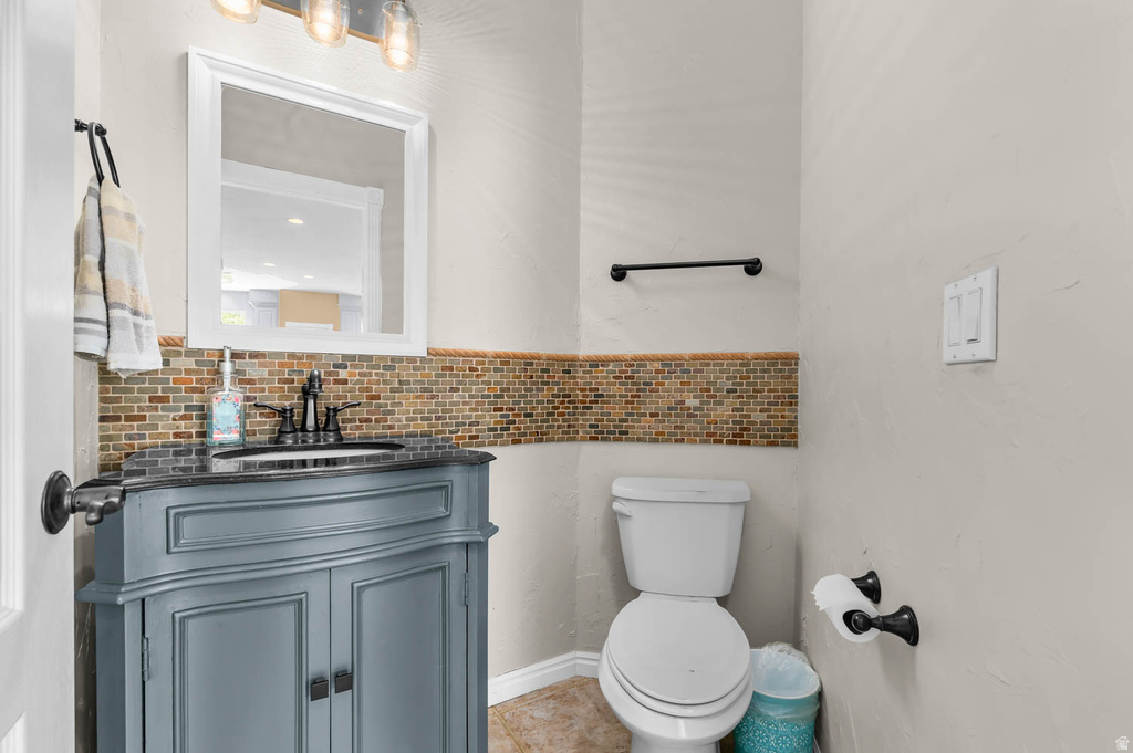 Bathroom featuring a gray vanity with a built-in sink, dark countertop, and mosaic tile backsplash