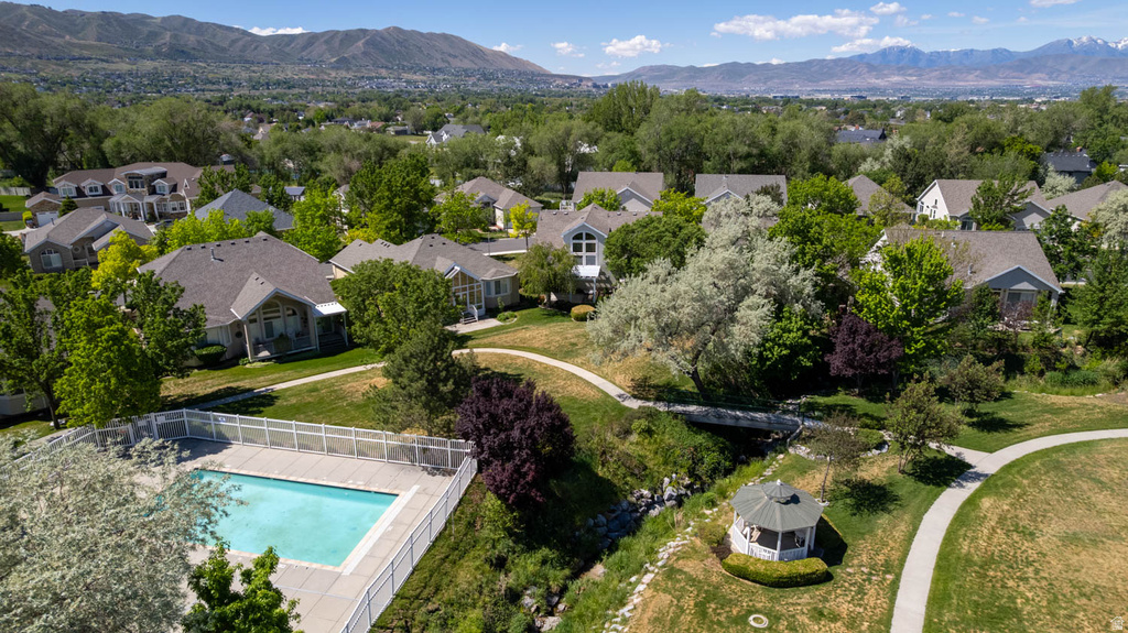 Community amenities featuring a fenced swimming pool, winding paved pathways, a decorative gazebo, and a footbridge over a stream