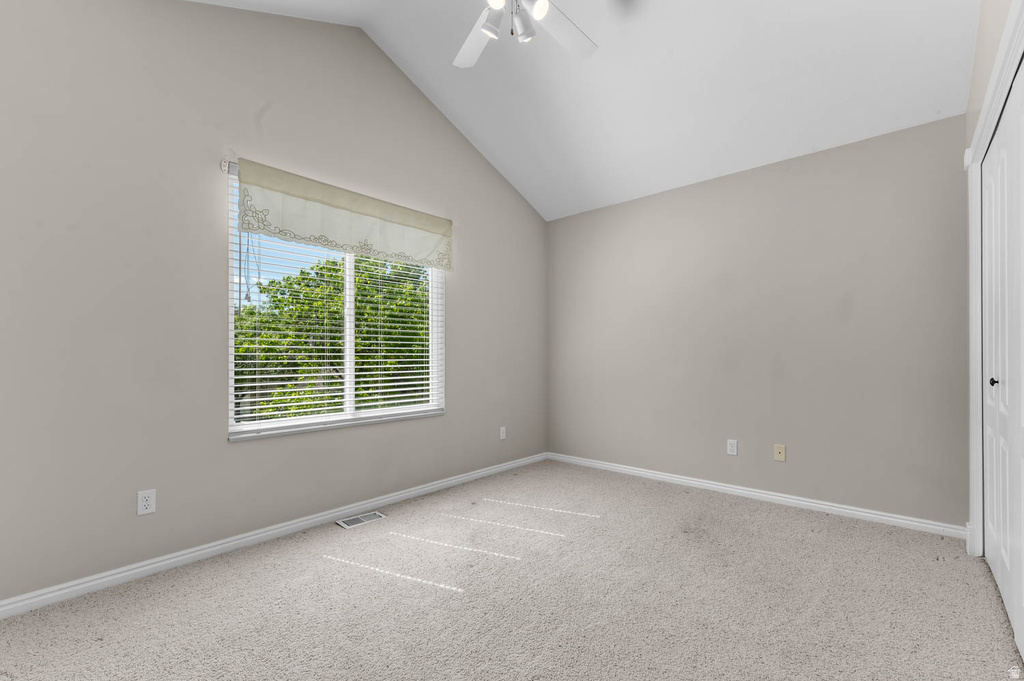 Vaulted ceiling bedroom with a window featuring blinds and a valance