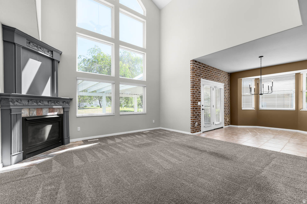 Vaulted ceiling living area featuring a fireplace with decorative mantel, expansive picture windows, and gray patterned carpeting