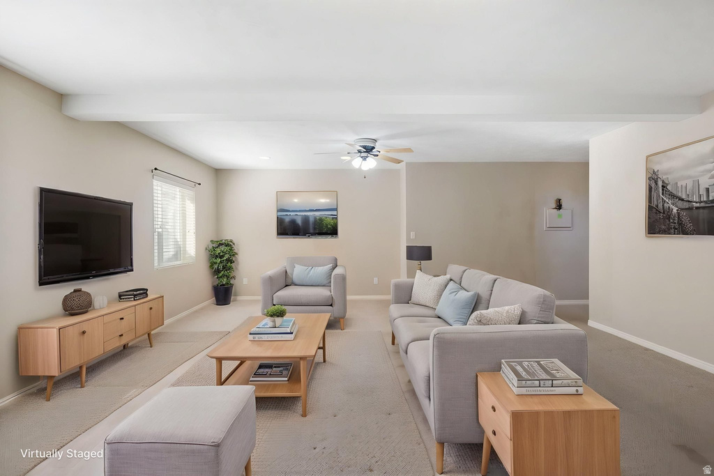 Spacious living area featuring light neutral wall tones, recessed ceiling beams, and a ceiling fan with integrated lighting