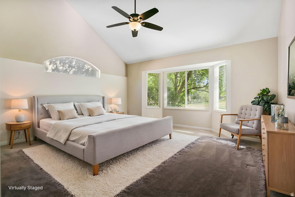Vaulted ceiling bedroom with a ceiling fan, a prominent bay window, and an arched transom window