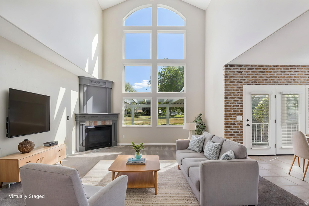 Vaulted ceiling living space featuring a corner fireplace with stone surround, a large arched window array, and French doors
