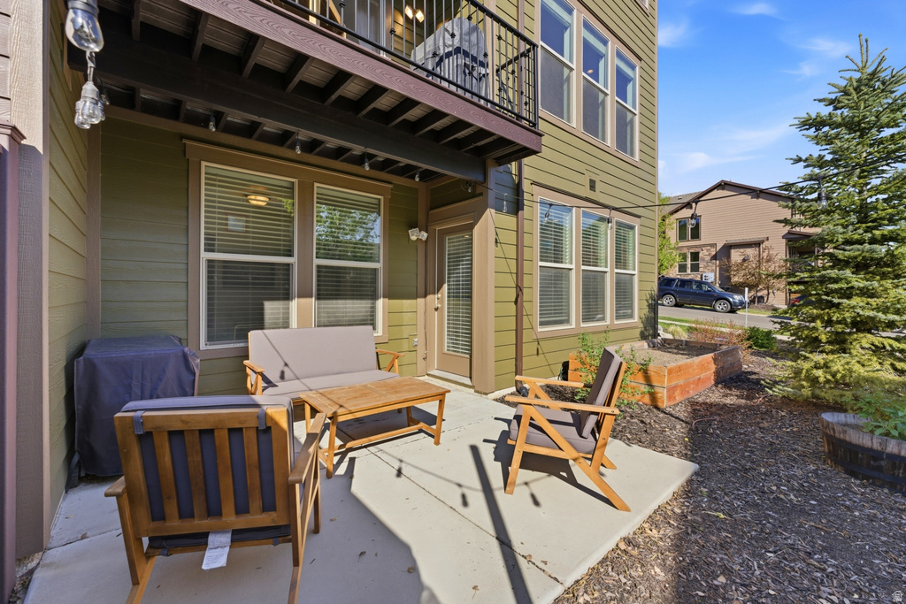 Private patio with concrete flooring, accented by an overhead balcony and string lighting