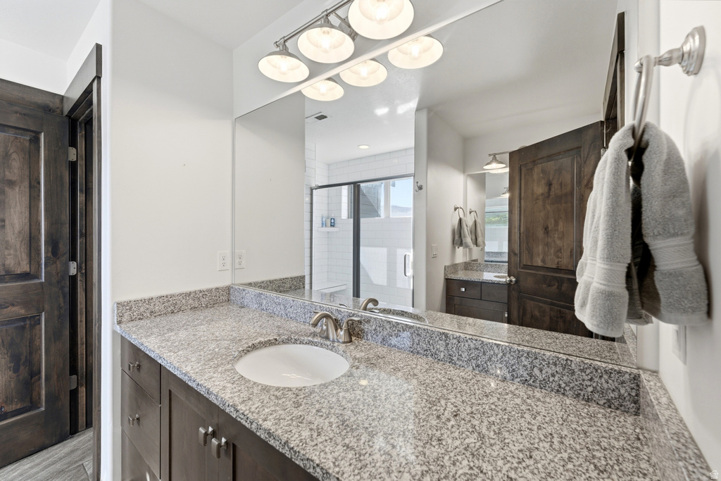 Bathroom vanity featuring a polished stone countertop with an undermount sink and brushed nickel faucet