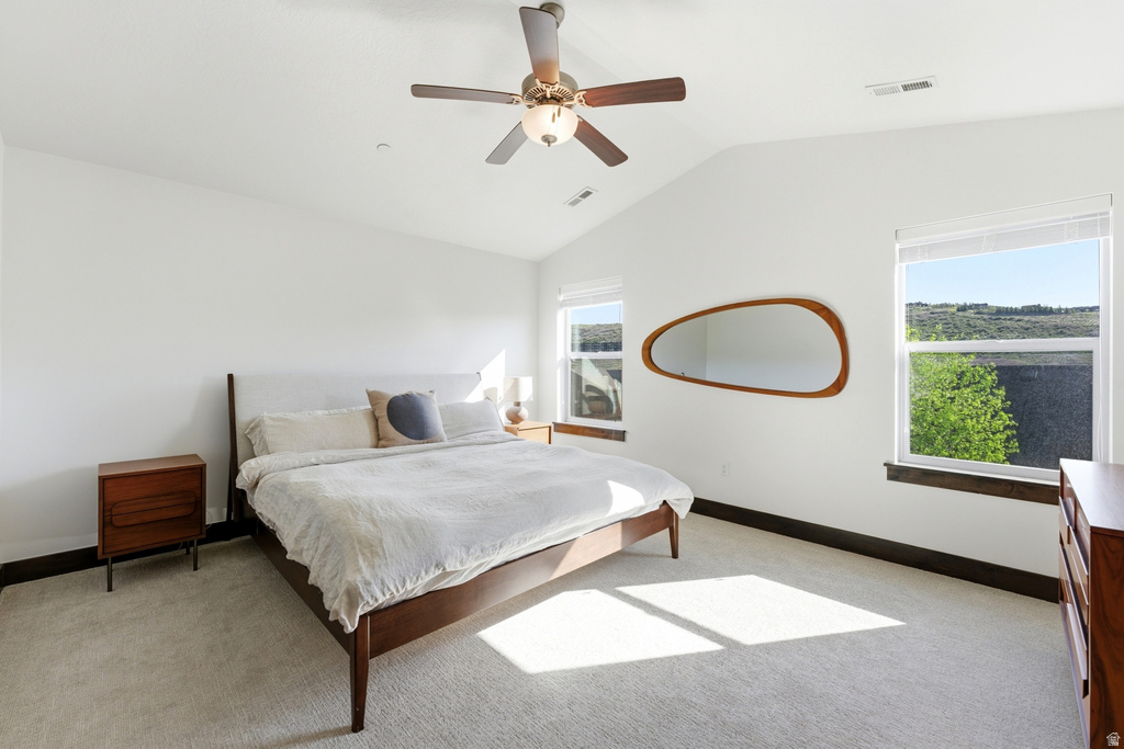 Vaulted ceiling bedroom with light-toned carpet flooring