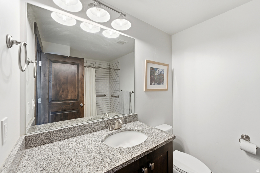 Bathroom featuring a granite countertop vanity with an undermount sink, brushed nickel faucet, and a large wall-mounted mirror