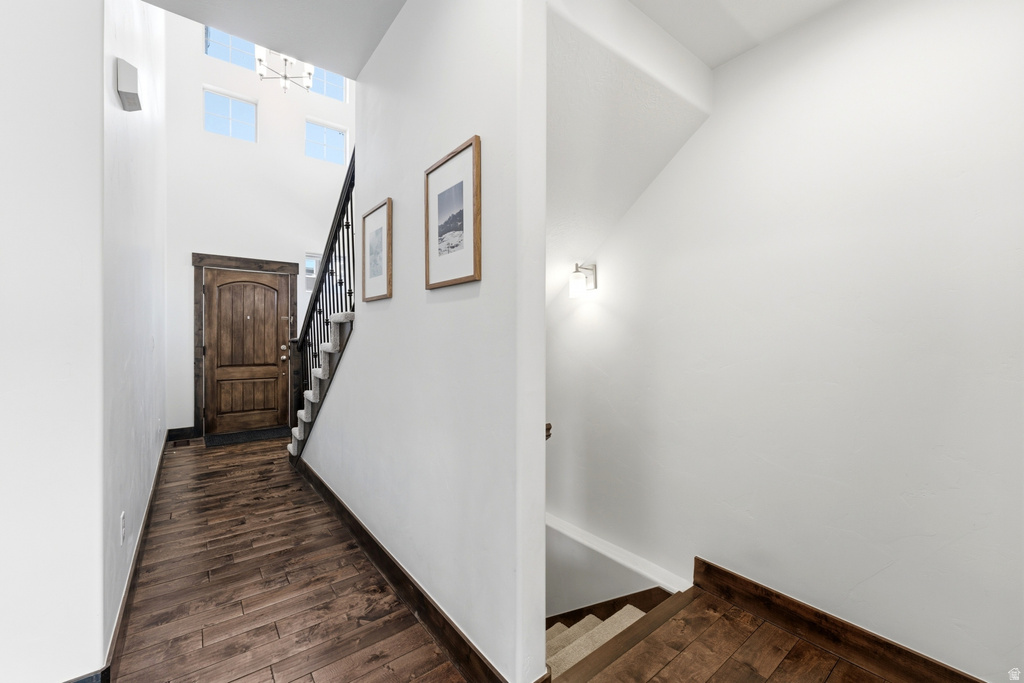Entryway featuring a wood-finish herringbone flooring, a carved wooden door, and a staircase with wrought iron balusters