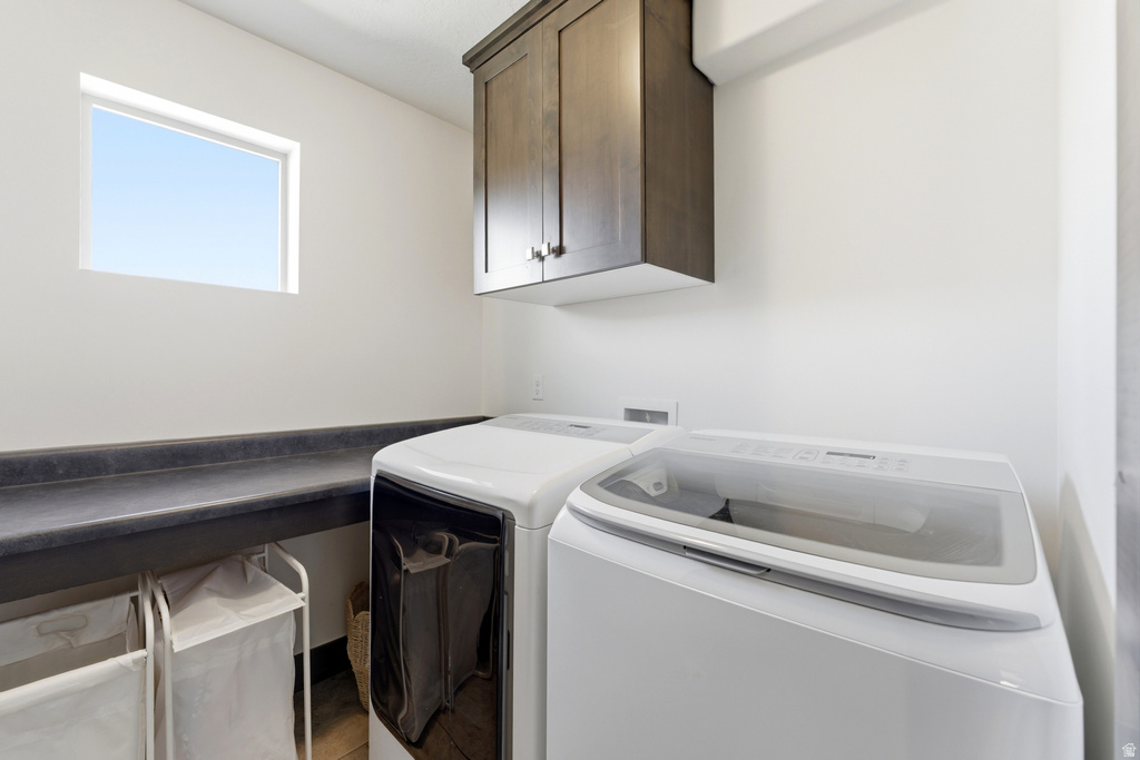 Dedicated laundry space featuring a built-in countertop, upper cabinetry with dark wood-finish doors, and a rectangular window