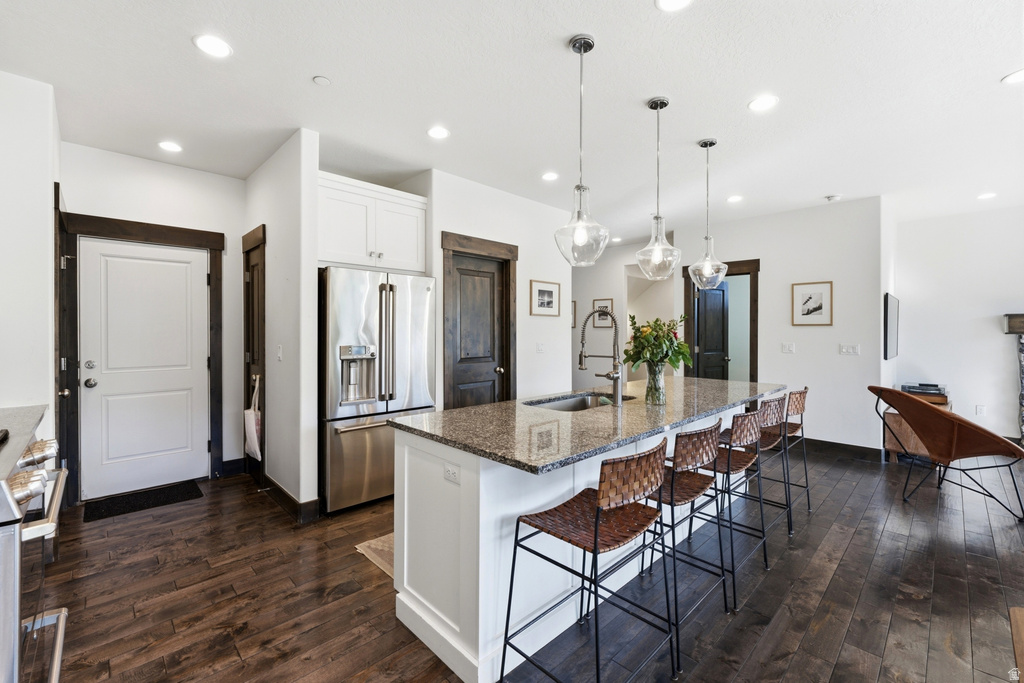 Open-concept kitchen featuring a large island with seating, granite countertops, stainless steel appliances, and wood-finish flooring