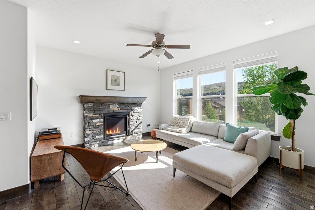Living area featuring a stone fireplace with a wood mantle, wood-finish flooring, recessed lighting, and a ceiling fan