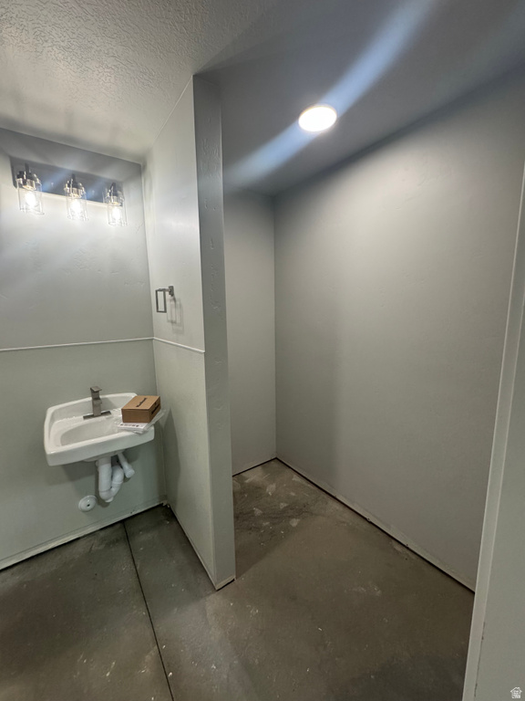 Wall-mounted sink with modern faucet, industrial-style vanity lighting, recessed ceiling light, and light gray wall paint
