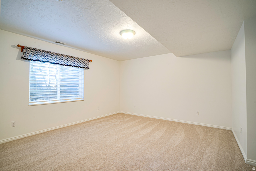 Carpeted room featuring a single window with blinds and a valance, light-colored walls, and a ceiling-mounted light fixture