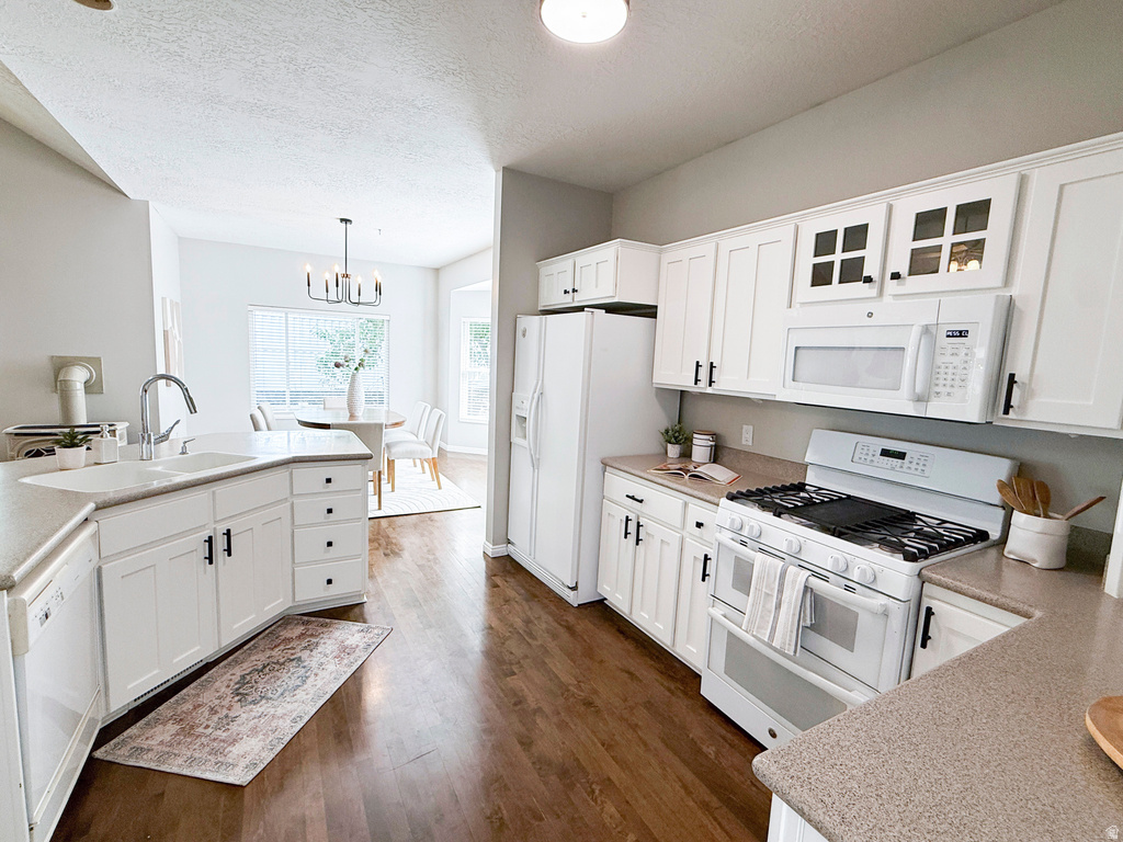 Kitchen featuring white cabinetry with black hardware, stone-finish countertops, stainless steel sink with gooseneck faucet, and wood-finish flooring