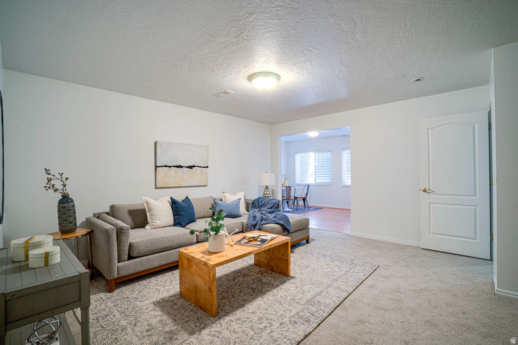 Carpeted living area featuring a neutral color palette, recessed lighting, and a white paneled interior door