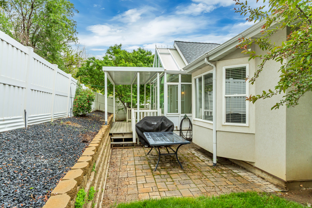 Patio area featuring paver flooring, a covered deck, and an adjacent sunroom