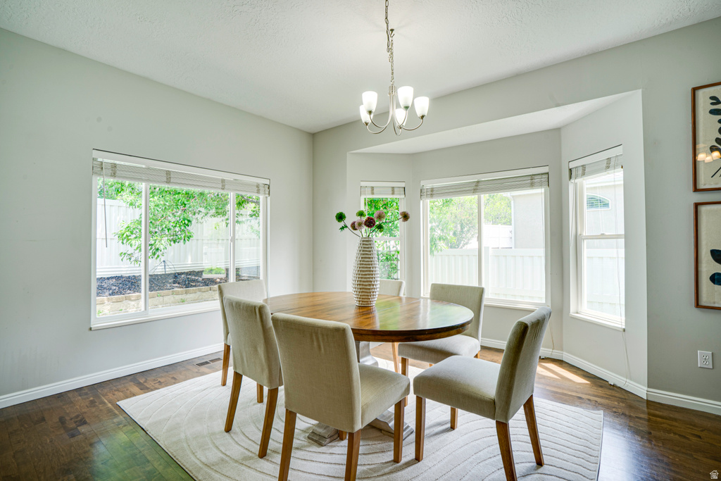 Dining area featuring a bay window, wood-finish flooring, light grey walls, and a multi-arm chandelier