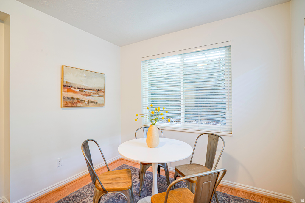 Recessed window with horizontal blinds, light wood-finish flooring, and white baseboard trim